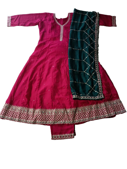 Pink and green traditional outfit with intricate patterns on a tiled floor.