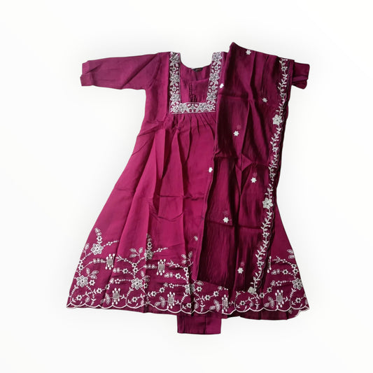 Maroon traditional outfit with white embroidery on a light gray floor.