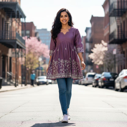 A woman wearing a purple kidshe short top with floral embroidery and a notched neckline, styled with blue jeans.
