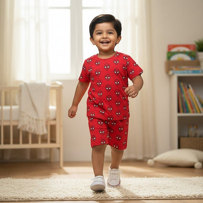 A happy toddler boy wearing a red kidshe Spider-Man print cotton coord set with shorts and a t-shirt in a nursery.